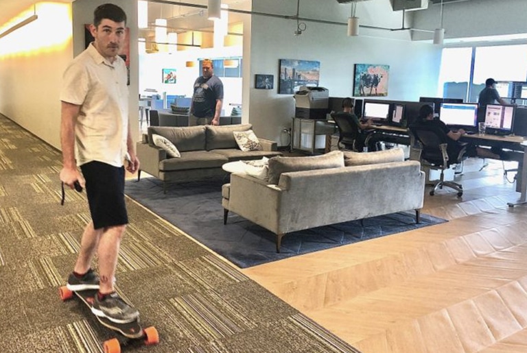man riding longboard in office
